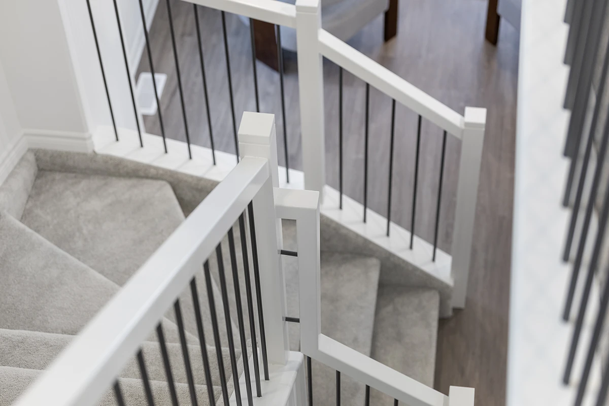 White staircase with black metal balusters and stained wood handrail.