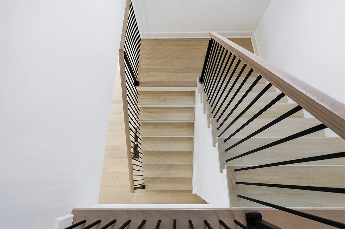 Stair landing with stained wood handrails and black metal balusters.