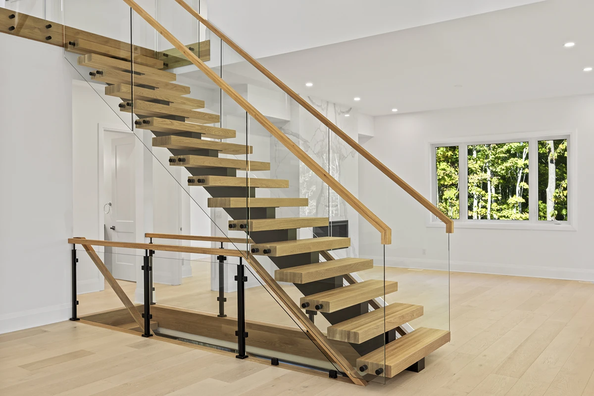 Floating oak staircase with frameless glass railings in a modern home.