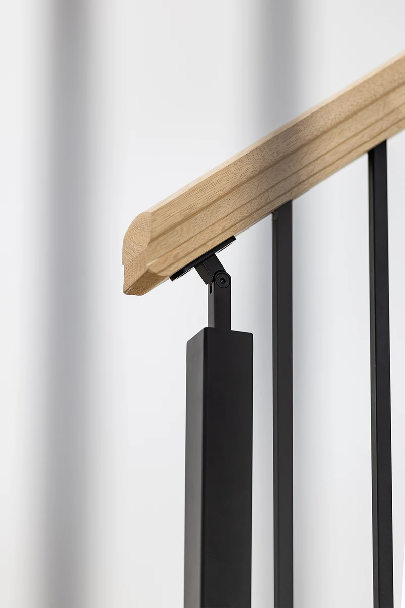Close-up of a stained wood handrail mounted to a black metal bracket.