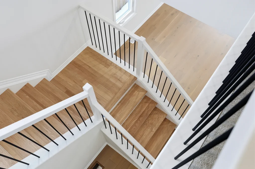 Overhead view of a staircase with white railings and black balusters.