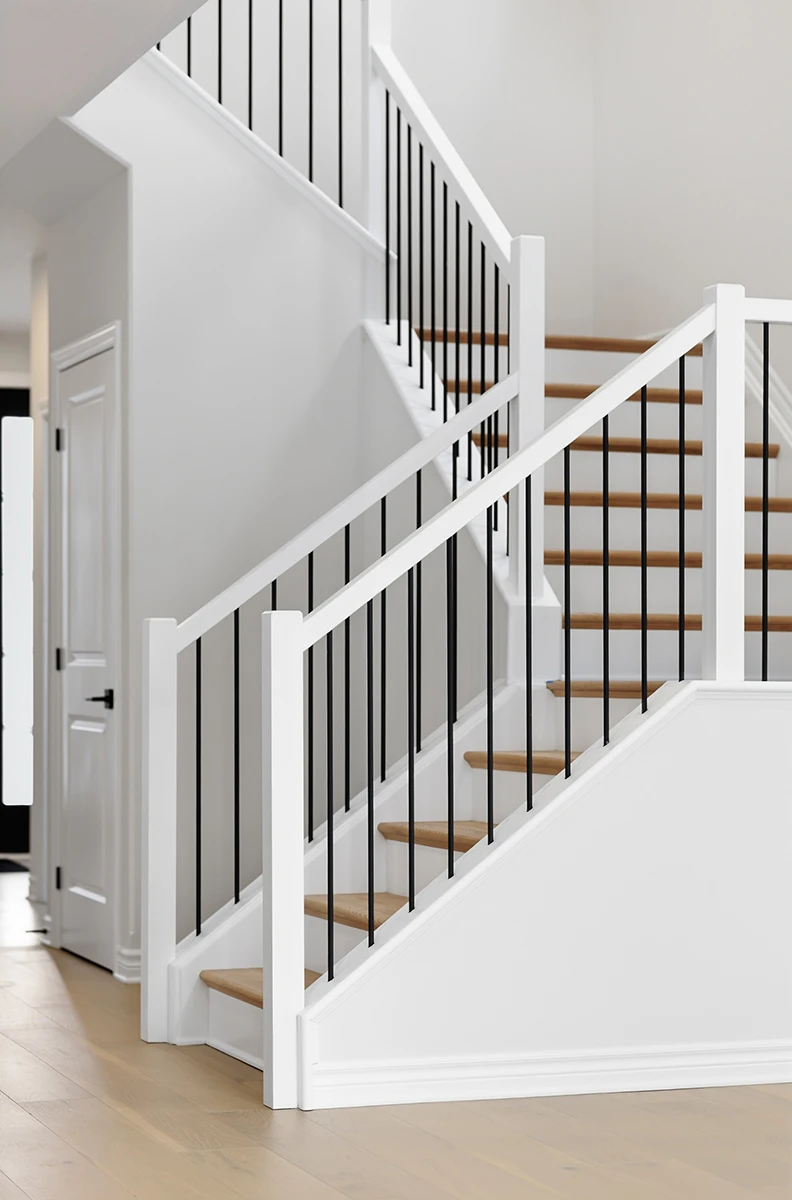 White staircase with black metal balusters viewed from above.