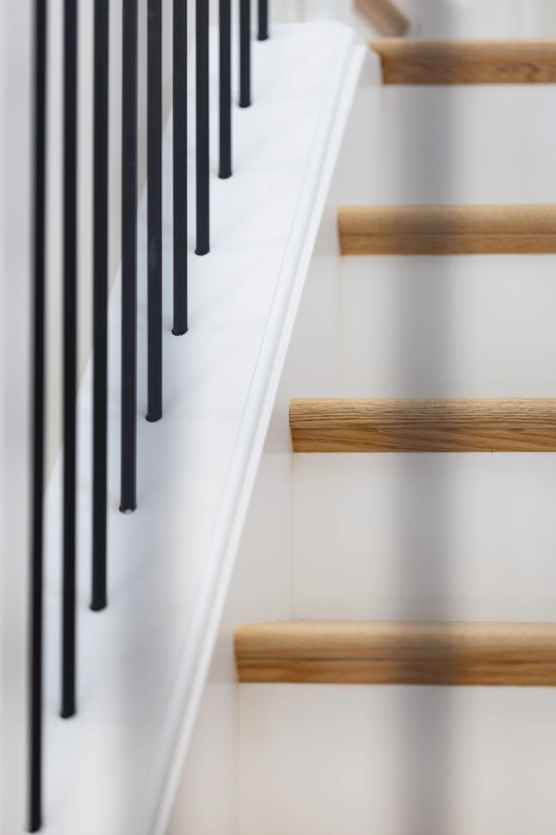 Close-up of black metal balusters on a wood staircase.