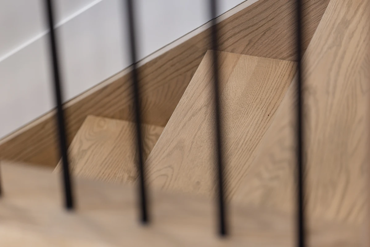 Close-up of stained wood handrail against black-framed glass.