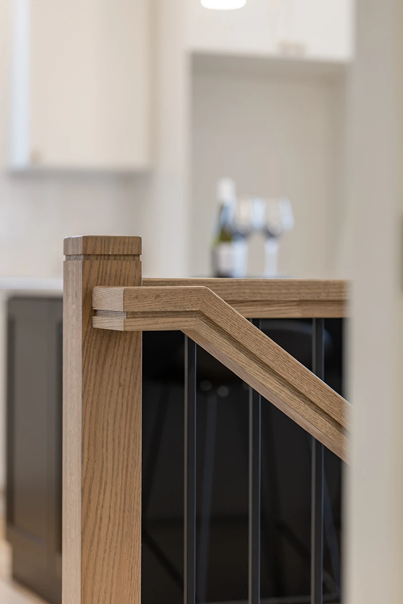 Square wood newel post with stained wood handrail.