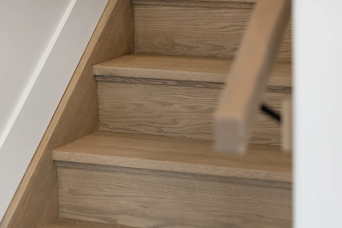 Hardwood stair treads with white risers and wood handrail.