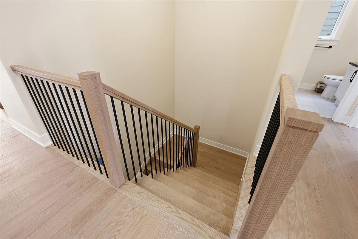 Finished wood staircase with black metal railings.