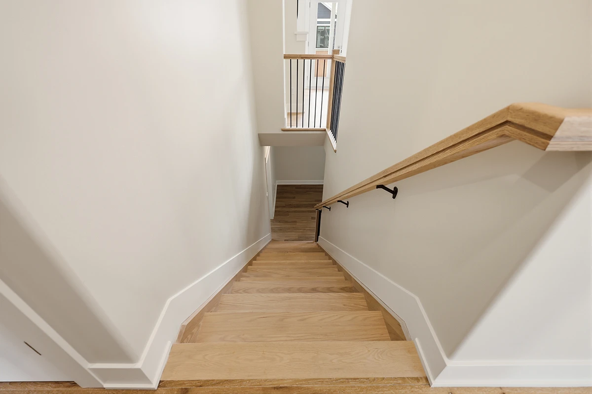 Hardwood staircase with wall-mounted wood handrail.