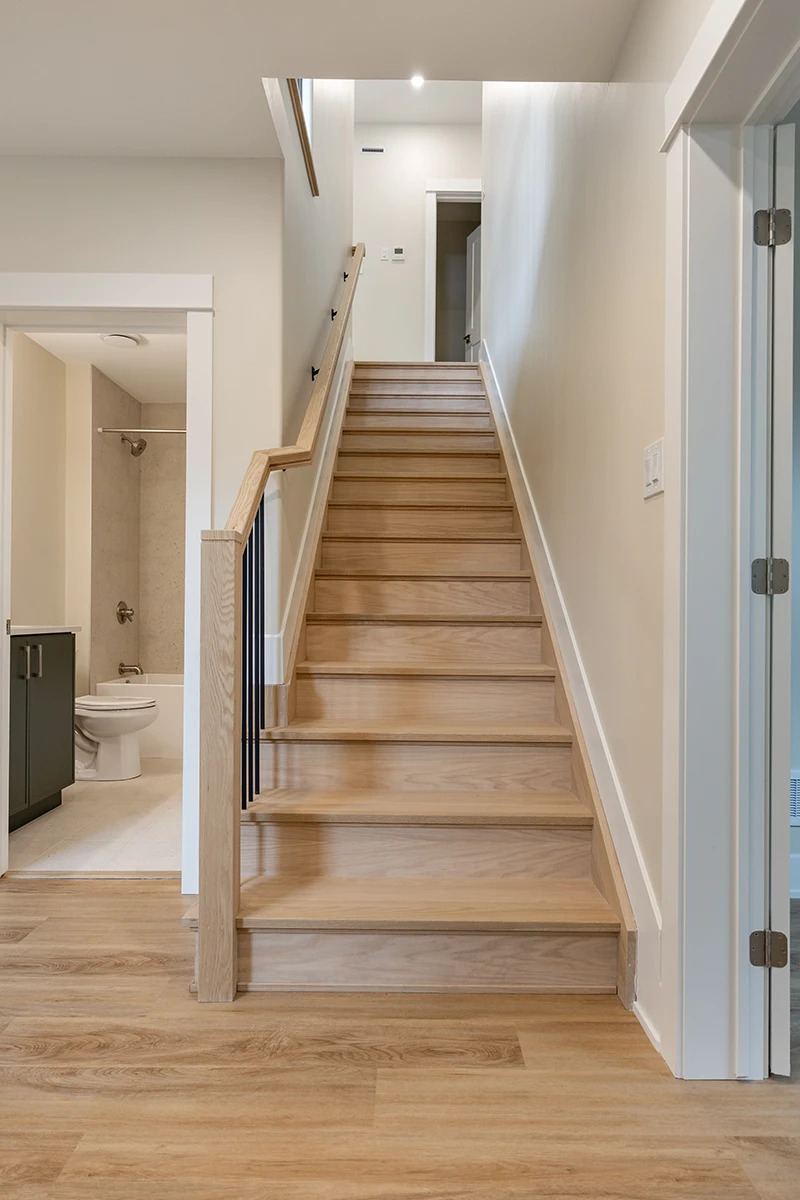 Straight wood staircase with black metal railings.