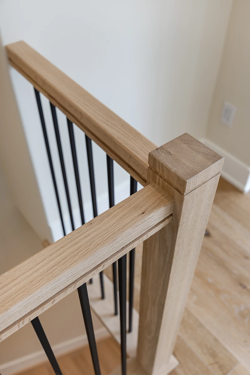 Close-up of stained wood handrail and square newel post.
