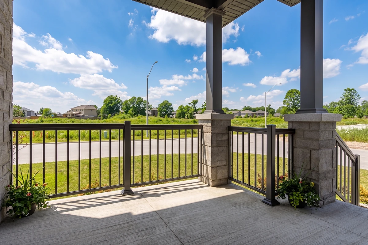 Covered porch with black aluminum railings overlooking a neighbourhood.
