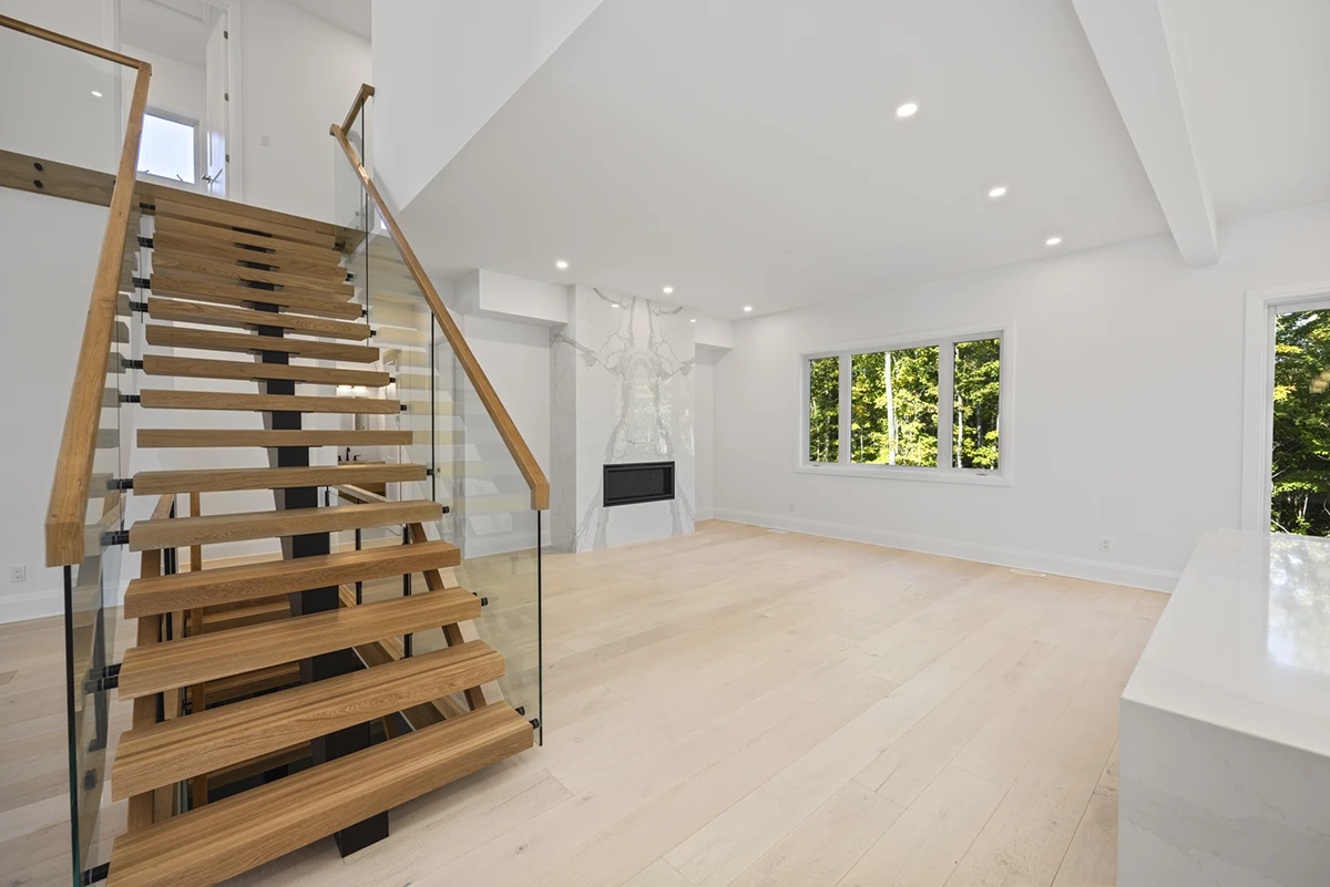 Floating staircase with thick oak treads and frameless glass railings.