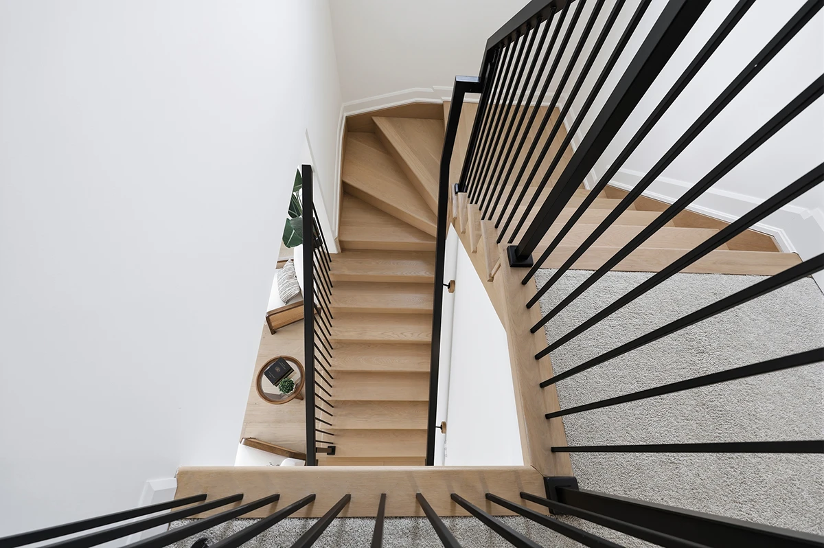 Staircase with black metal railings in a bright residential entryway.