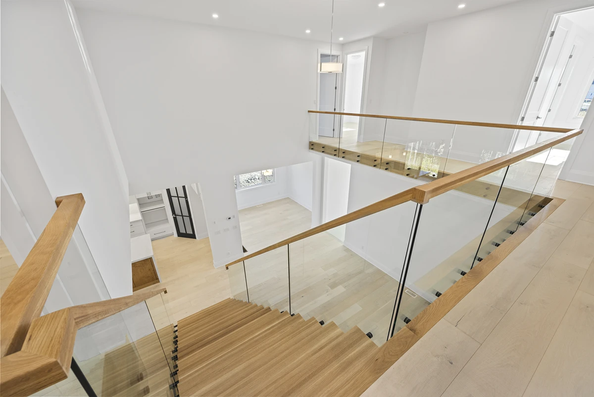 Upper-level view of a floating staircase overlooking a modern kitchen.