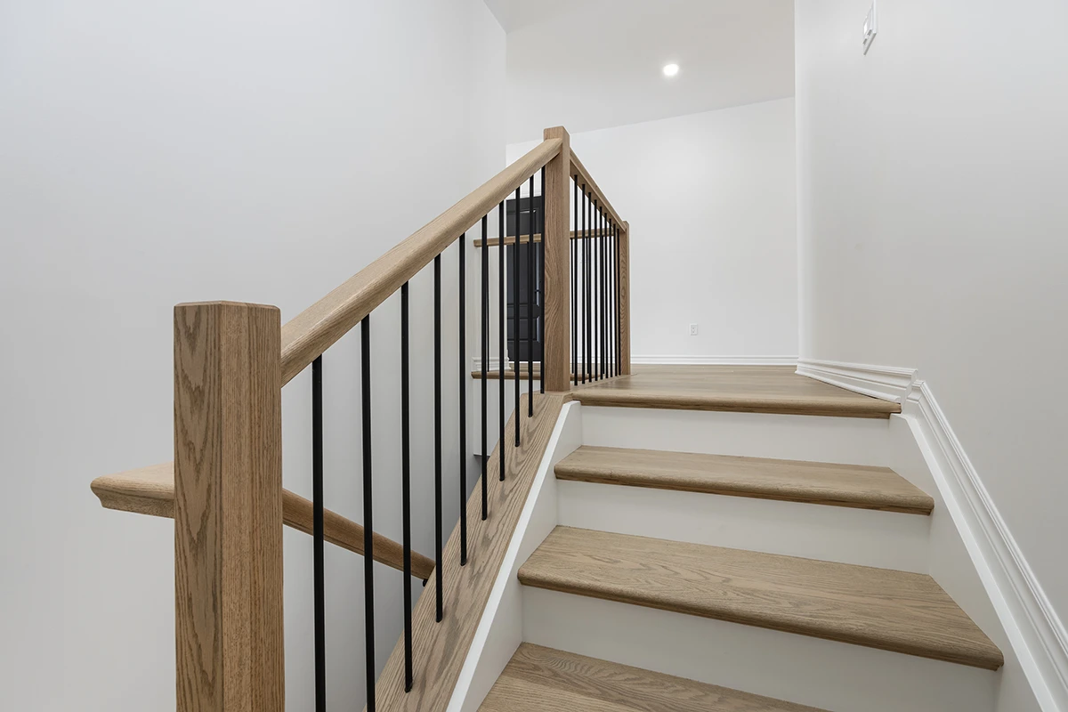 Stair landing with black metal railings and stained wood handrails.