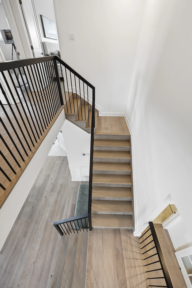 Stair landing with wood treads and black metal railings viewed from above.