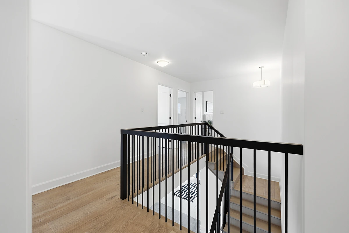 Upper-level landing with black metal guardrails and open-concept layout.