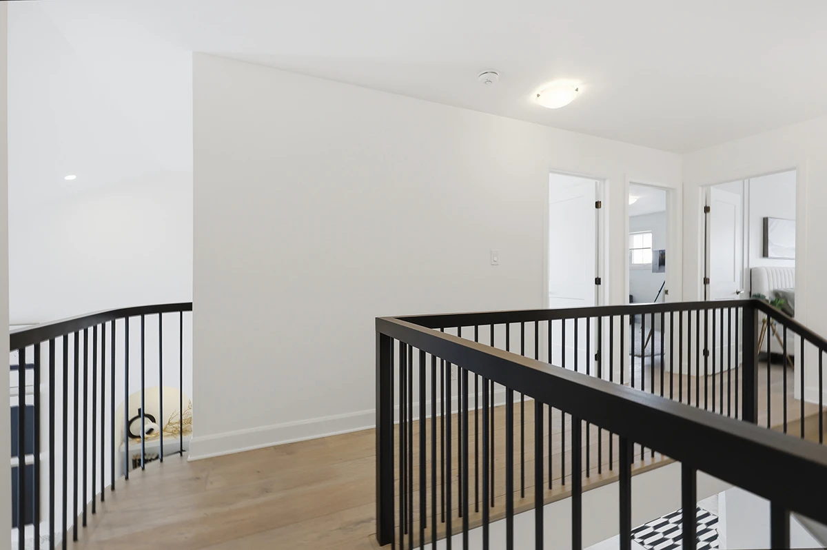 Bright loft overlooking a staircase with black metal railings.