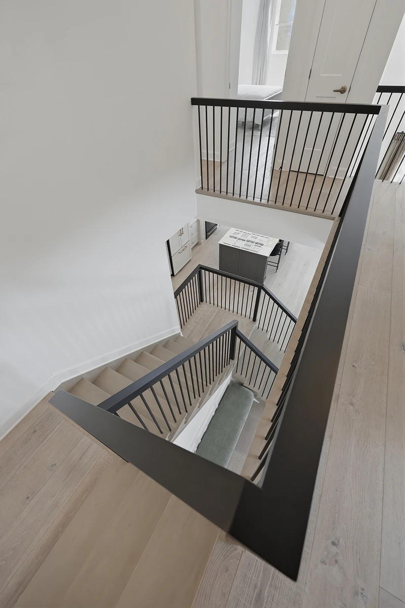 Stair landing overlooking a lower level with black metal railings.