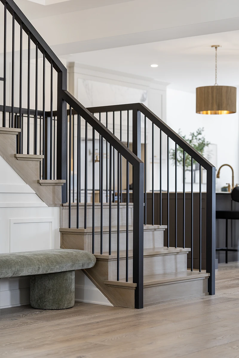 Modern staircase with black metal railings and hardwood treads.