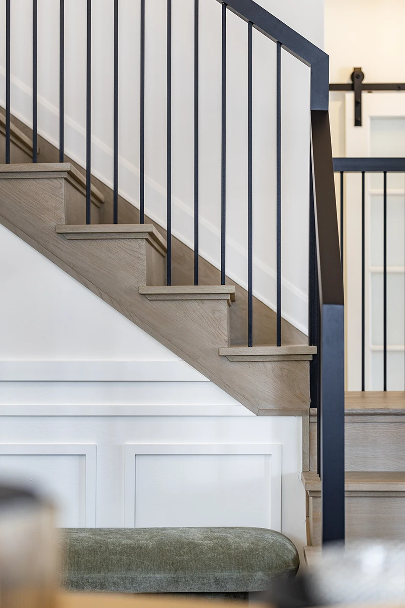 Carpeted staircase with black metal balusters and wood handrail.