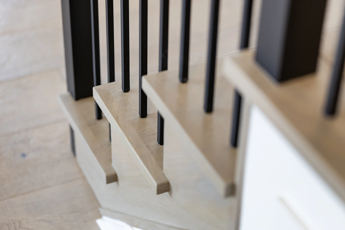 Close-up of black metal balusters on wood stair treads.