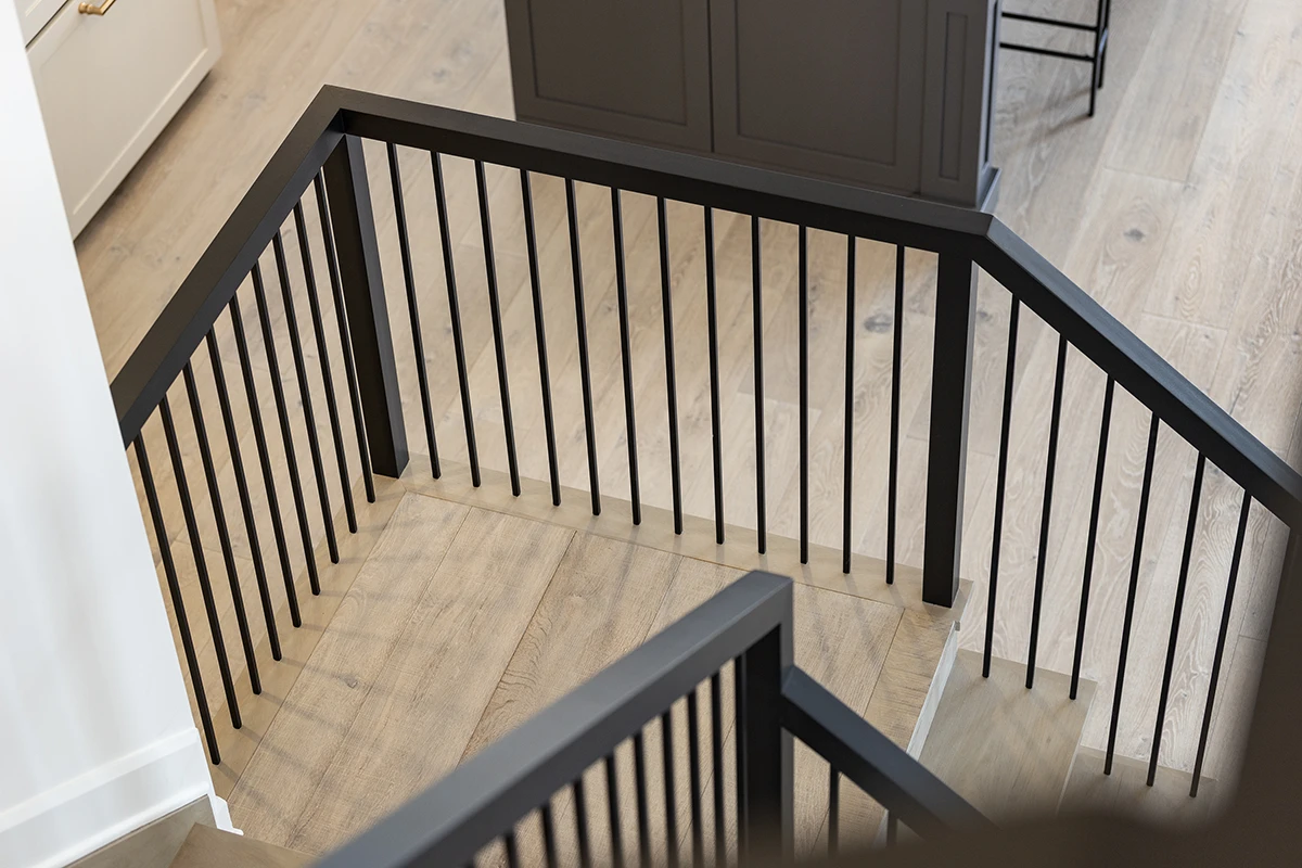Black metal stair railing with stained wood handrail.