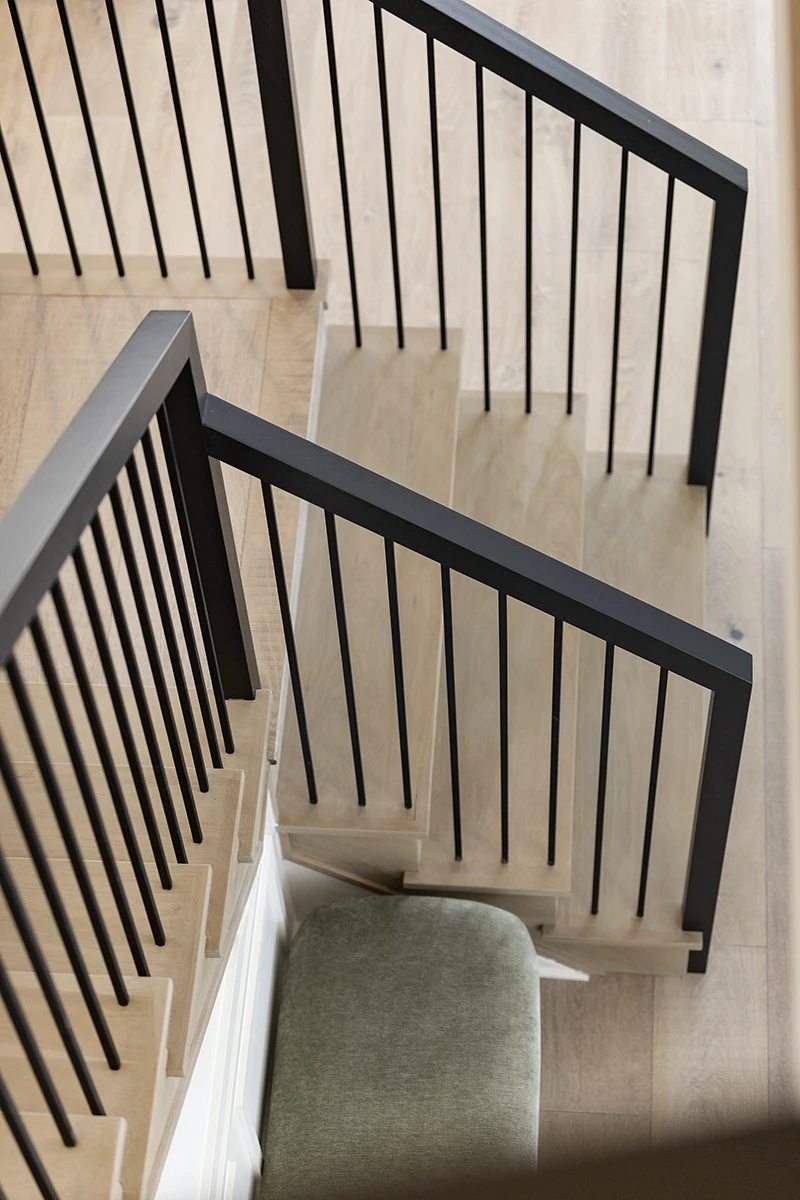 Black metal stair railing overlooking hardwood flooring.