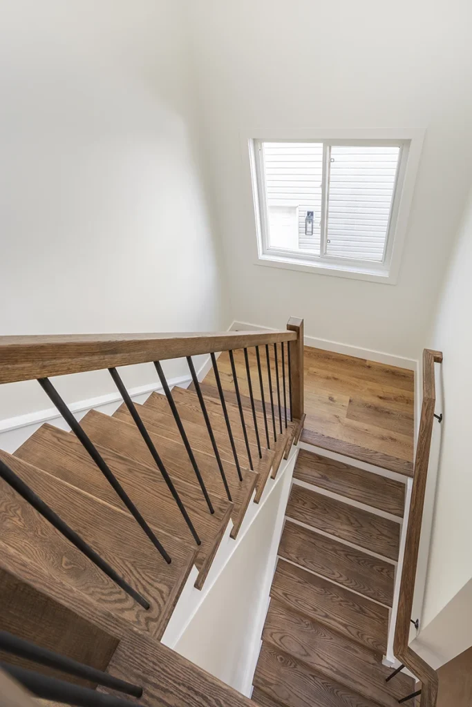 Overhead view of a residential staircase with wood treads and black metal railings.