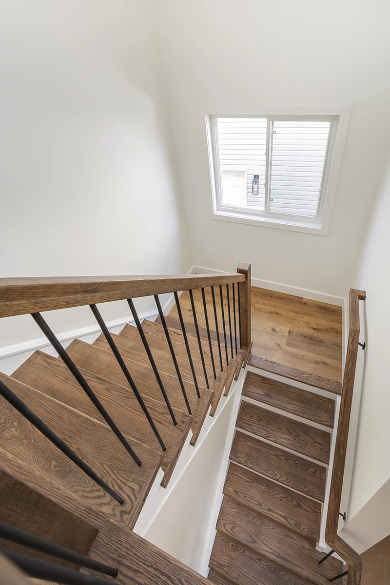 Overhead view of a residential staircase with wood treads and black metal railings.