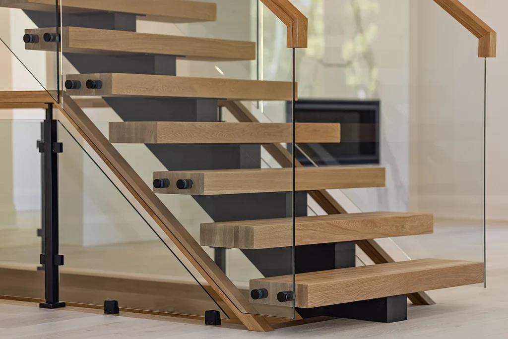 Floating staircase with oak treads and frameless glass railings viewed from above.