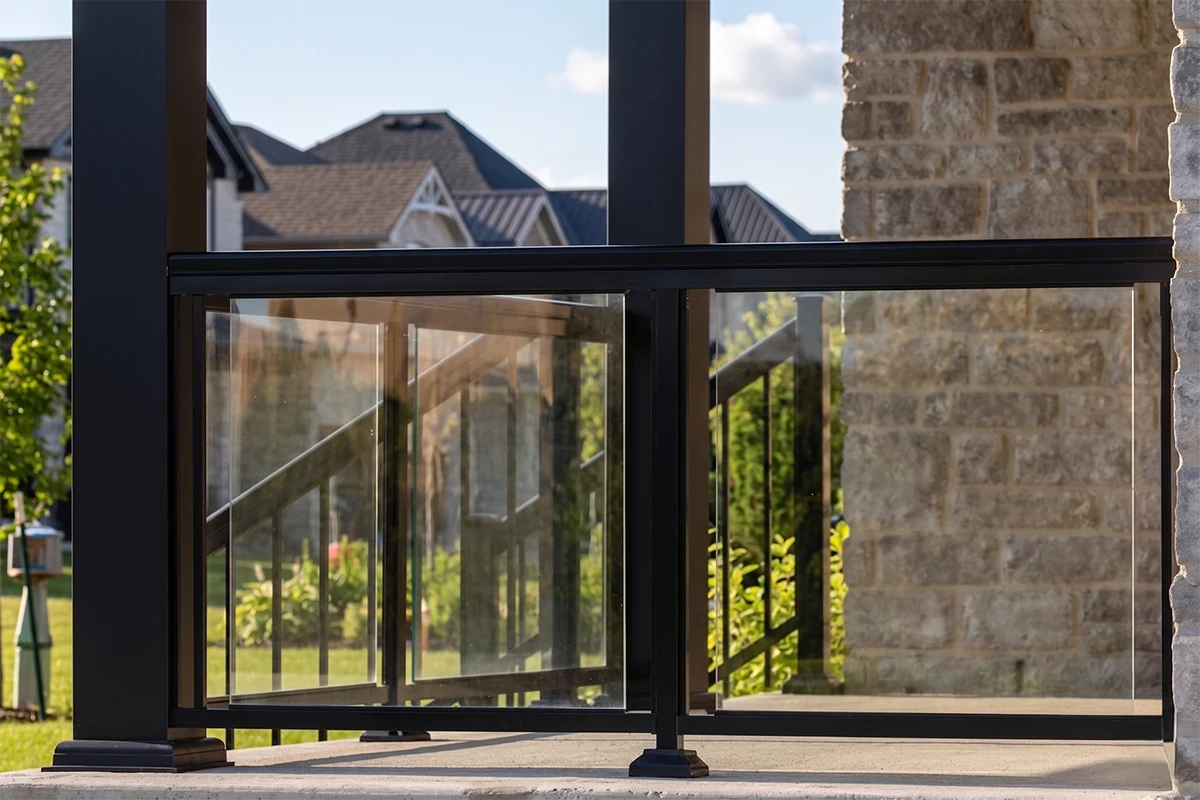 Exterior glass railing with black metal posts on a residential deck.