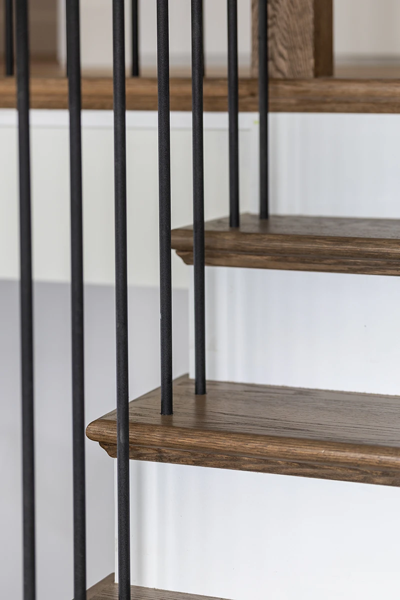 Square wood handrail with black metal balusters on a custom staircase.