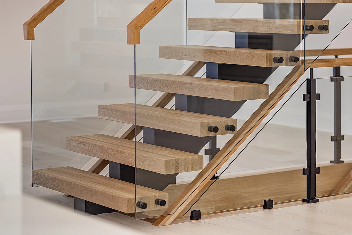 Floating oak staircase with frameless glass railings in a modern home.