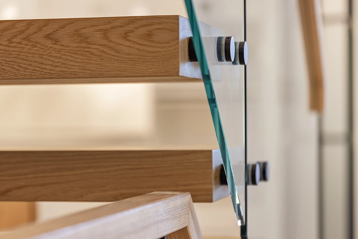 Stainless steel hardware securing a frameless glass stair railing.