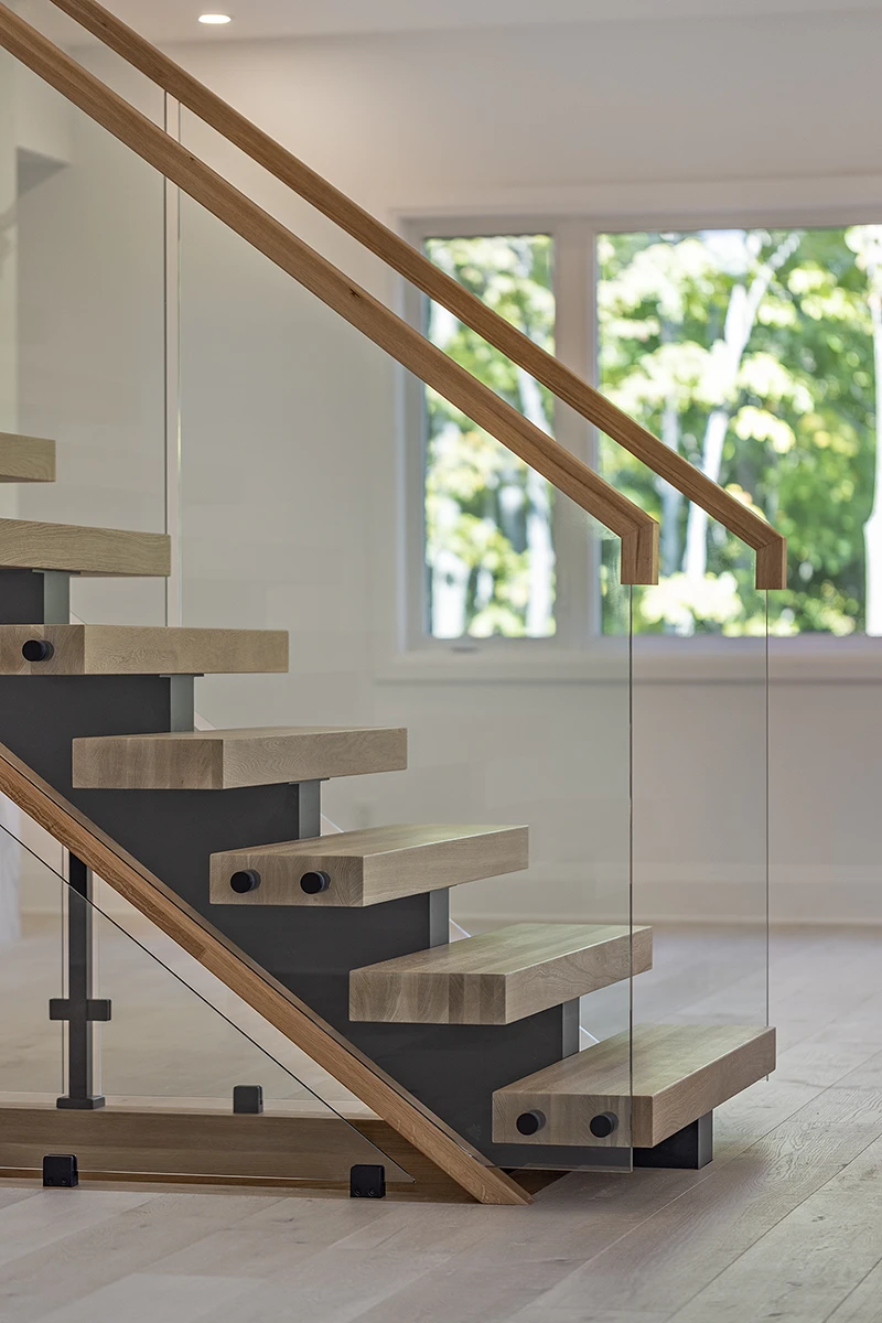 Floating staircase with frameless glass railing and black mounting hardware.