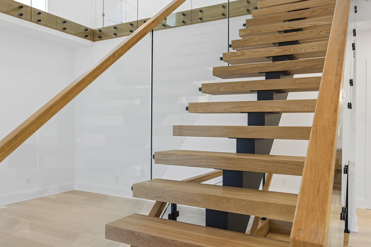 Floating oak staircase with thick wood treads and glass railings.
