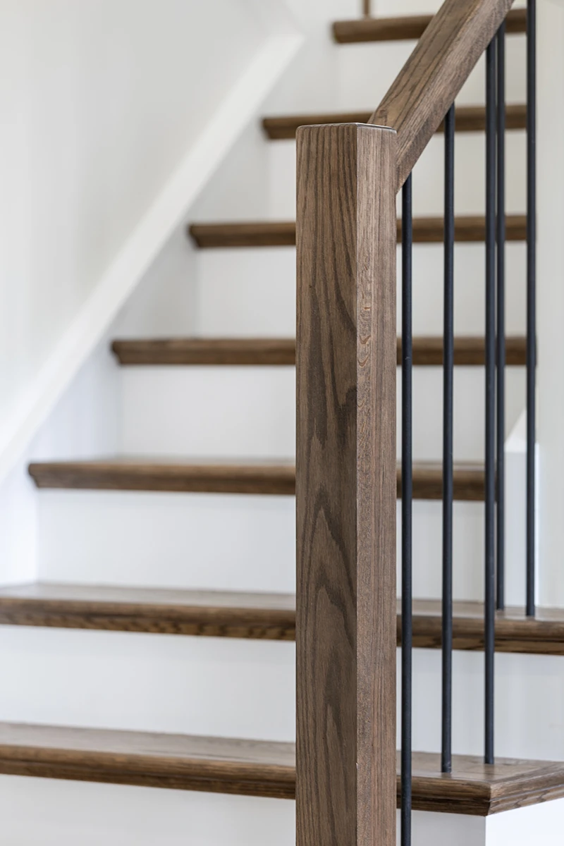 Close-up of stained wood stair treads and black metal balusters.