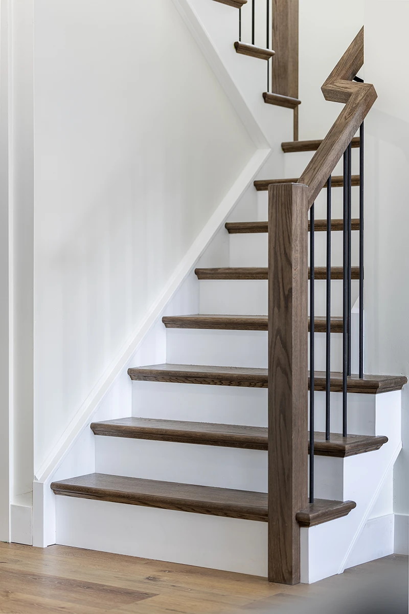 Wood staircase with black metal balusters viewed from the side.