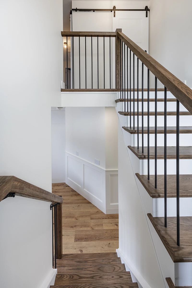 Wood staircase with black metal railings in a bright entryway.