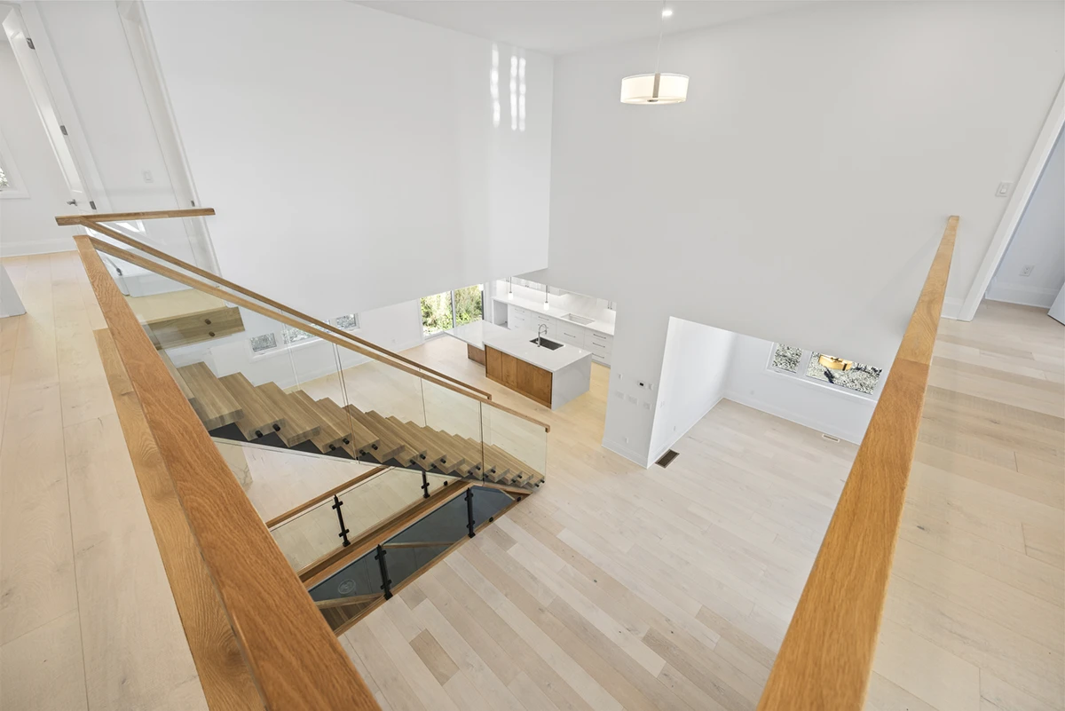 Floating staircase with glass railings beside an open-concept kitchen.