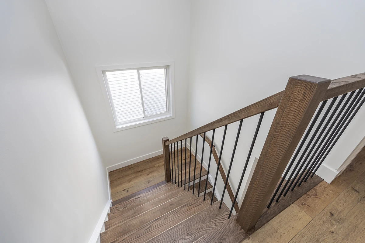 Upper landing with wood staircase and black metal railings.