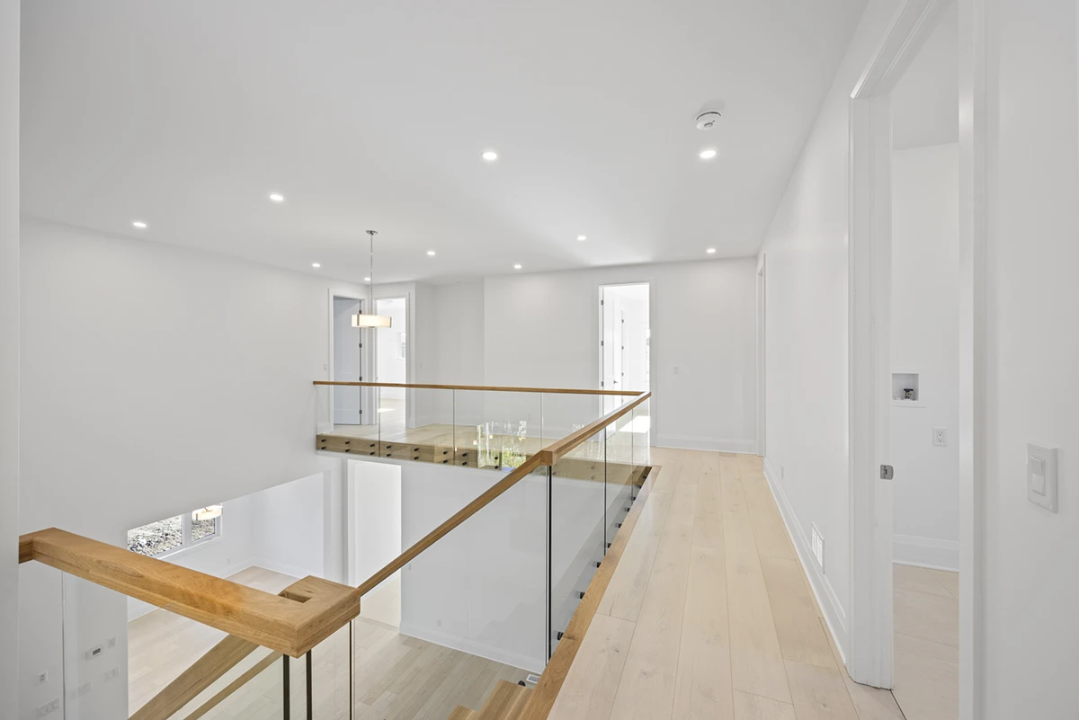 Floating staircase with frameless glass railings overlooking a modern kitchen.