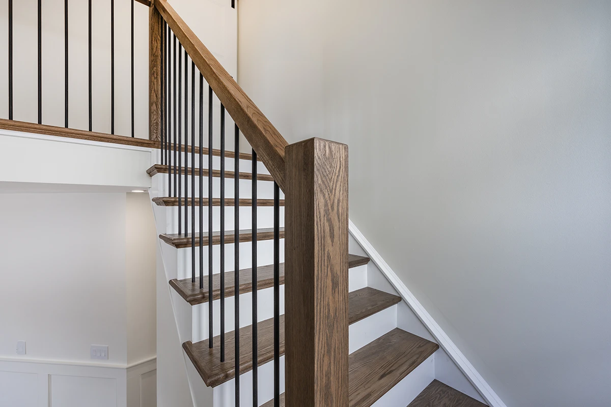 Staircase with black metal balusters and stained wood newel posts.