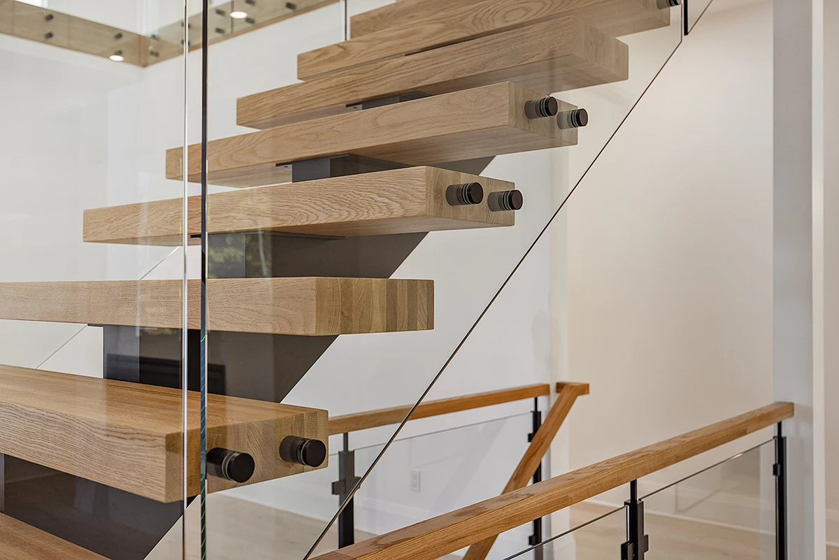 Close-up of floating oak stair treads with frameless glass railings.