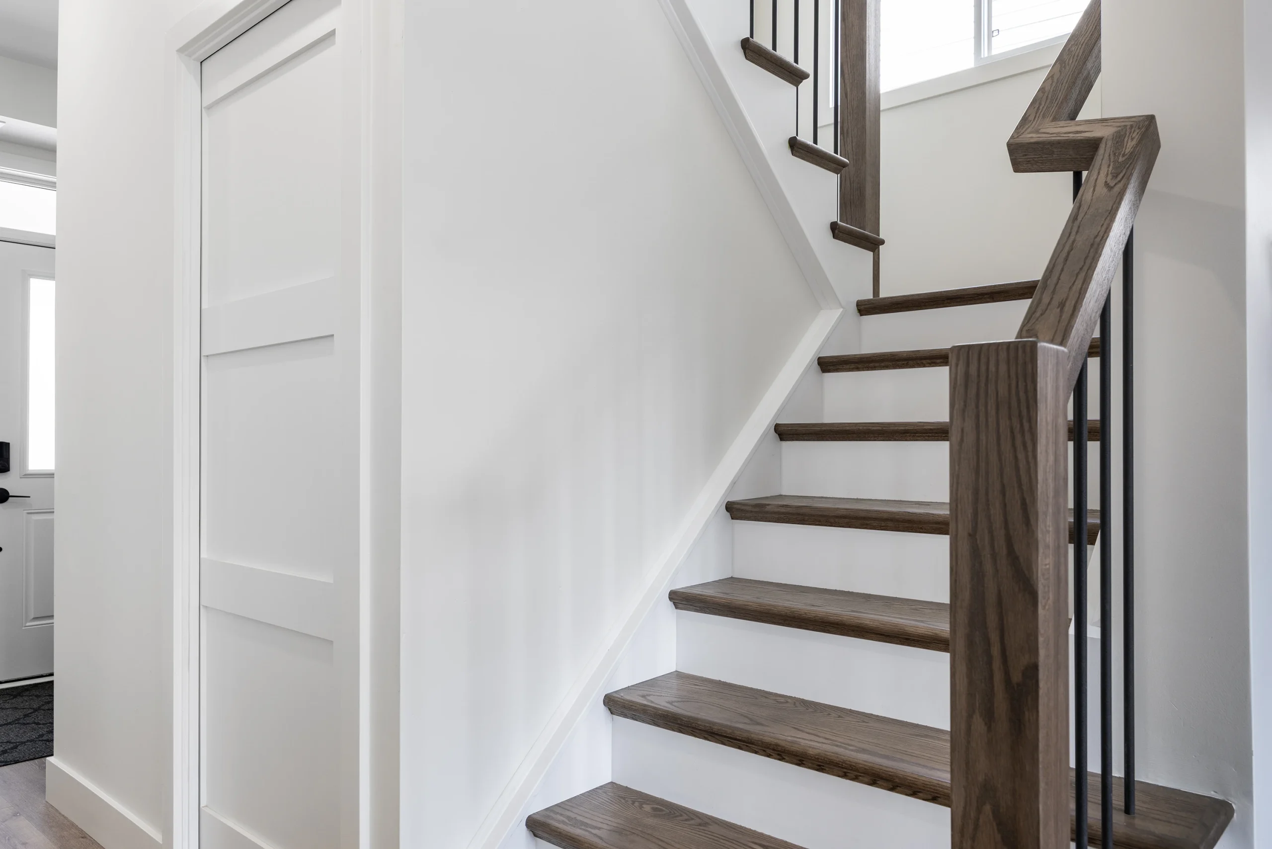 Modern staircase with stained wood treads and black metal railings.