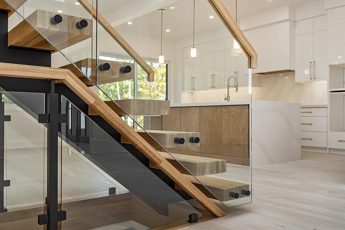 Floating staircase with oak treads and frameless glass railings.