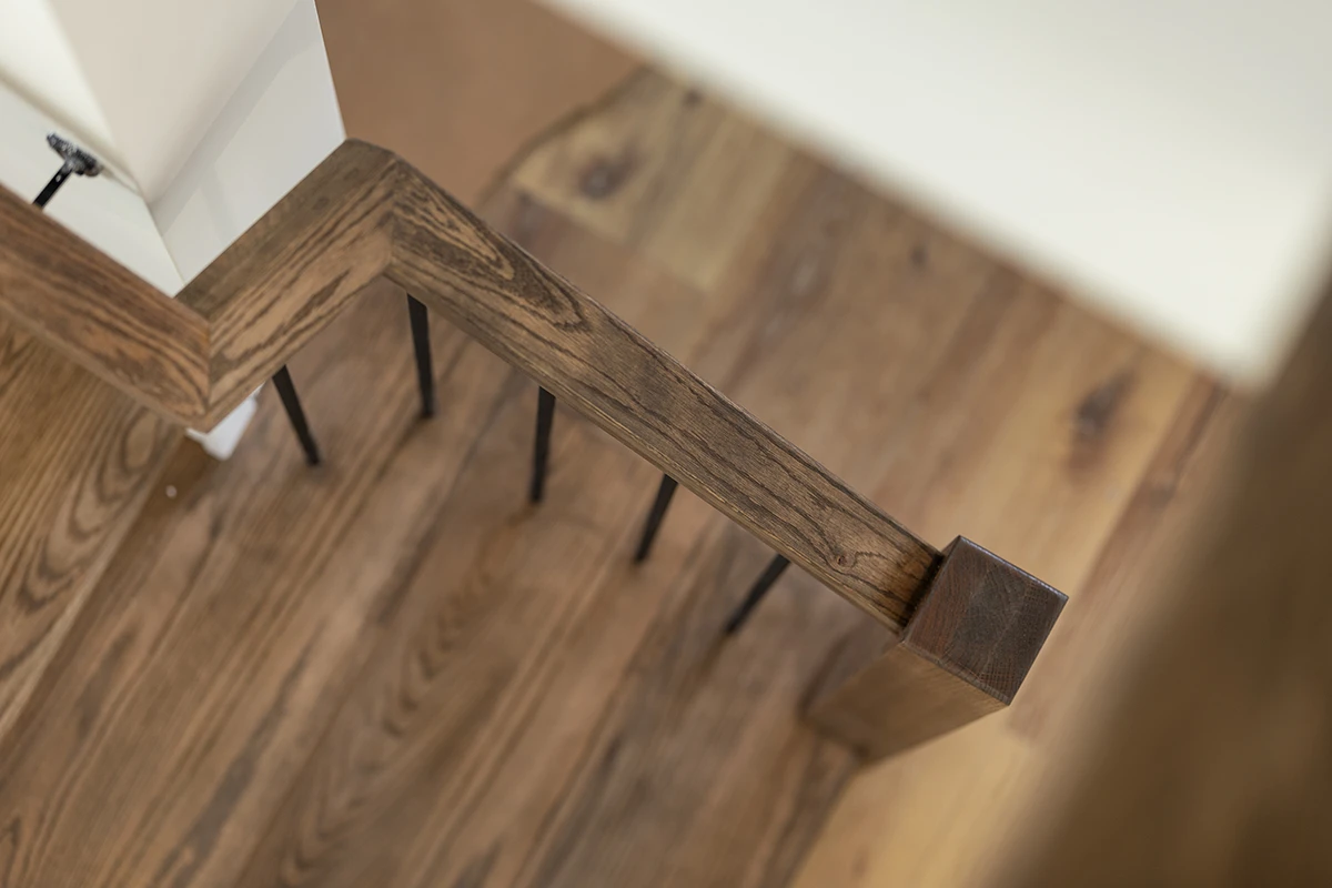 Overhead view of wood stair treads with black metal balusters.