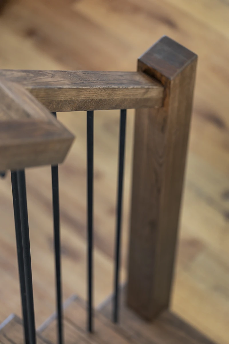 Wood handrail connection detail with black metal balusters.