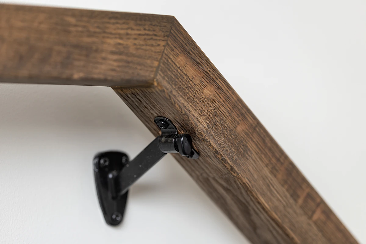 Close-up of a wood handrail fastened to black metal balusters.